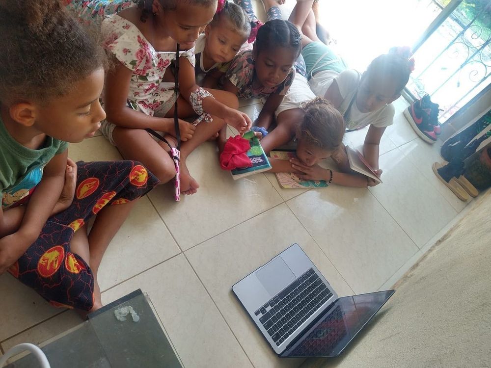 Niños reunidos en el piso alrededor de un computador