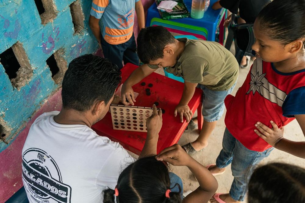 Niños jugando un juego de mesa con un voluntario