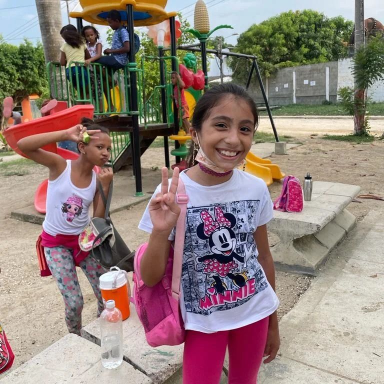 Niña haciendo la señal de paz en el parque