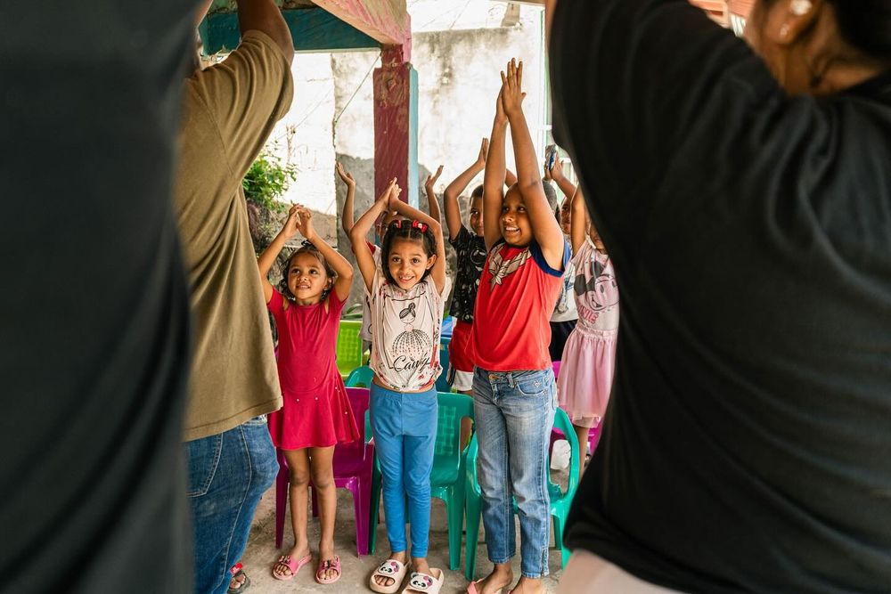 Niños con los brazos en alto durante una jornada